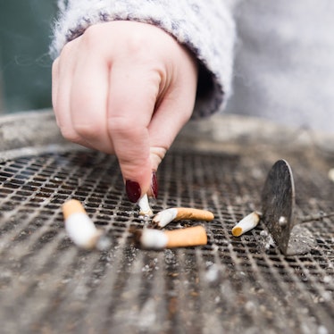 Eine Frau drückt eine Zigarette in einem Aschenbecher aus.