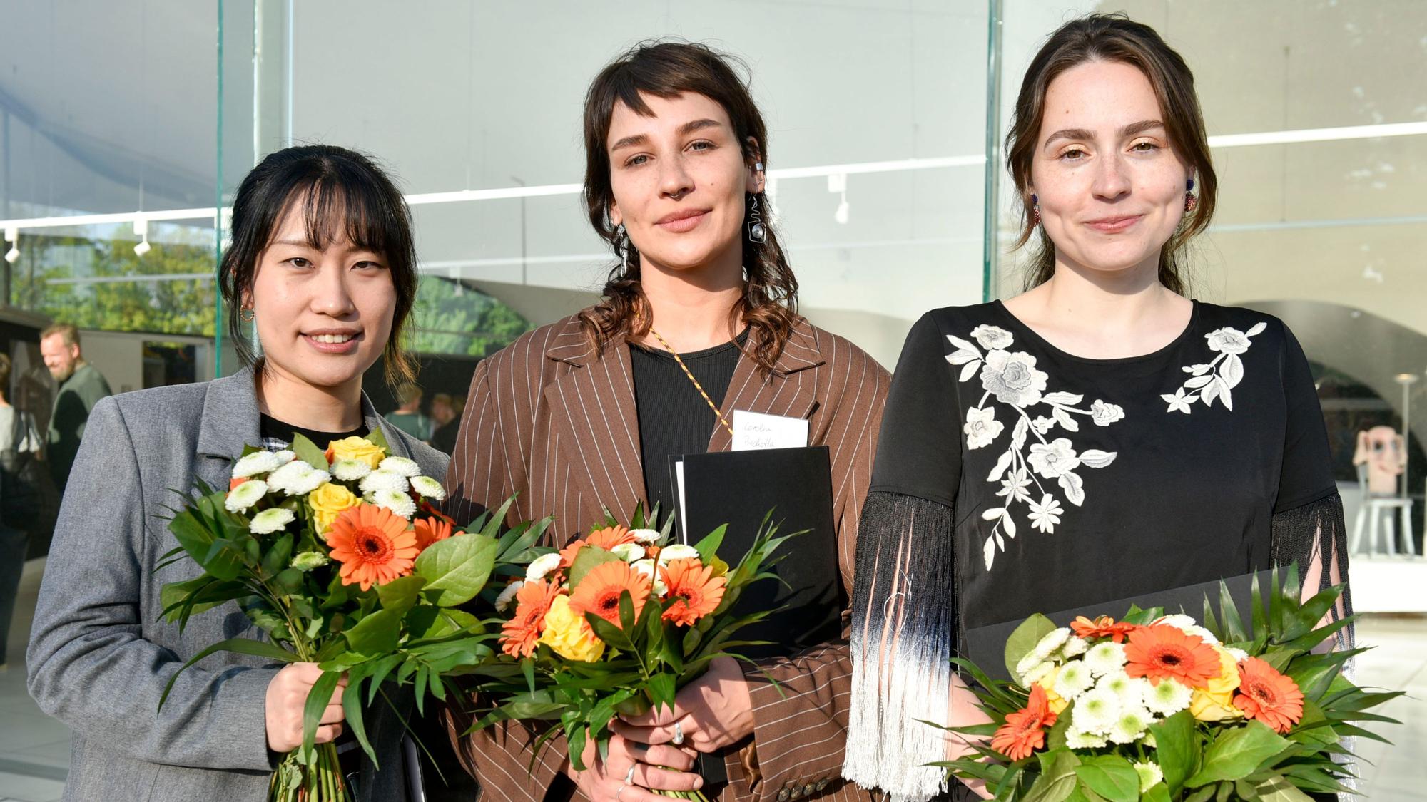 Auf dem Bild sind die drei Preisträgerinnen mit Urkunden und Blumensträußen zu sehen.