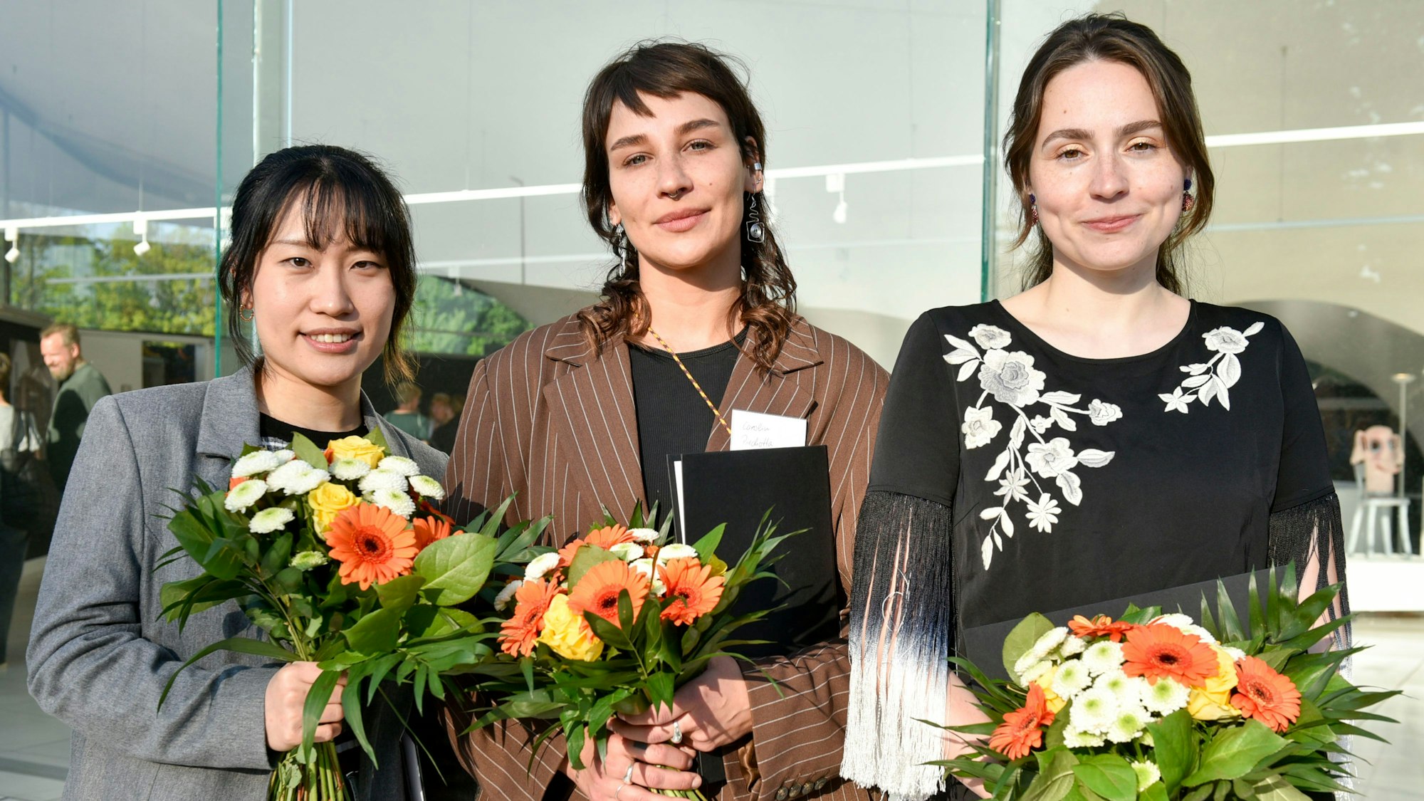 Auf dem Bild sind die drei Preisträgerinnen mit Urkunden und Blumensträußen zu sehen.