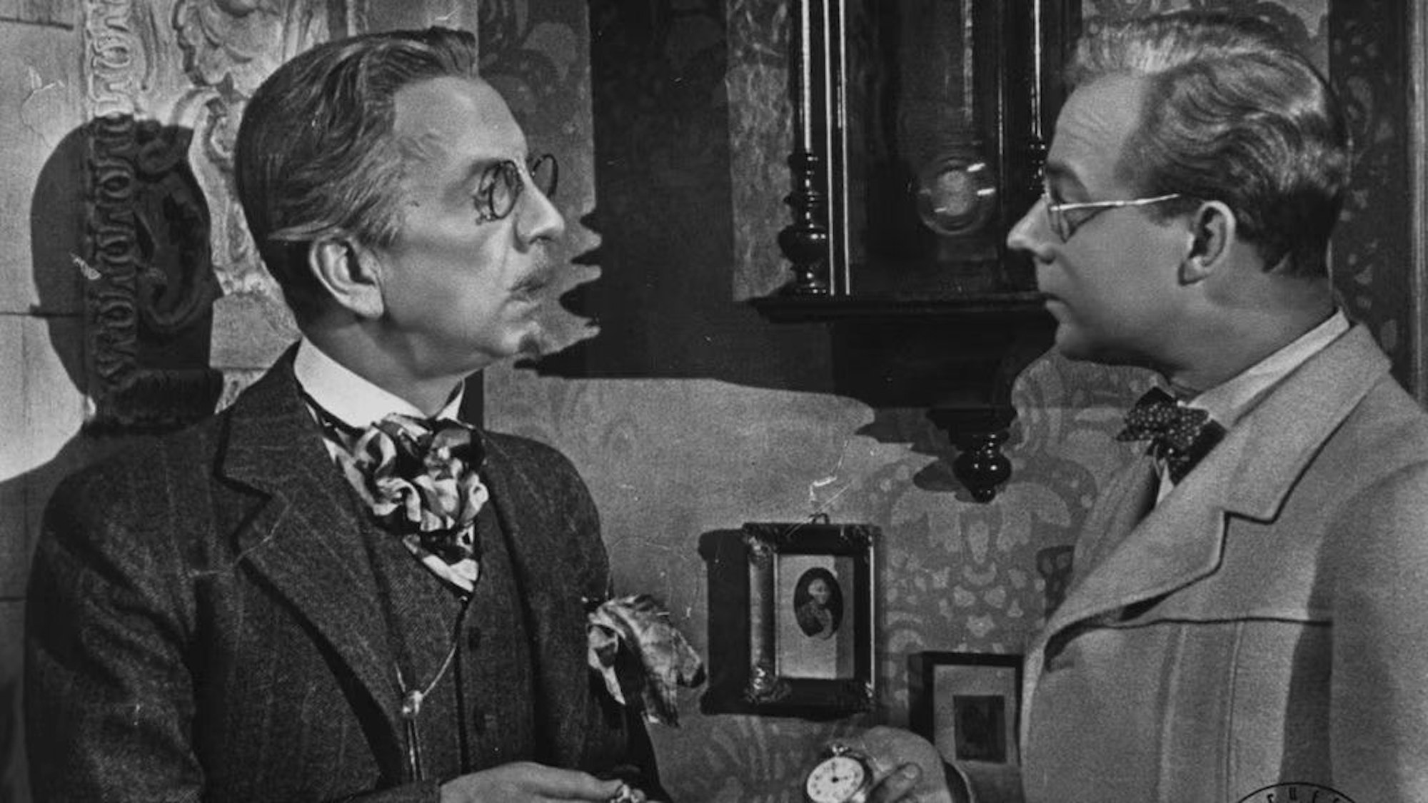 Schwarz-Weiß-Aufnahme aus dem Film „Die Feuerzangenbowle“: Erich Pontos steht in seiner Rolle als Professors Crey Heinz Rühmann gegenüber.