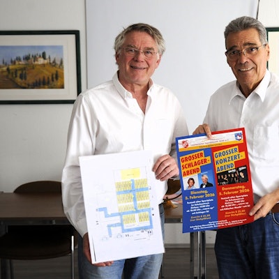 Zwei Männer halten ein Plakat und einen Plan.