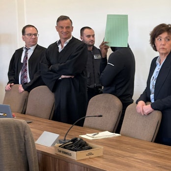 Die drei Angeklagten mit Verteidigern, Dolmetscherin und Wachtmeister beim Prozess im Kölner Landgericht