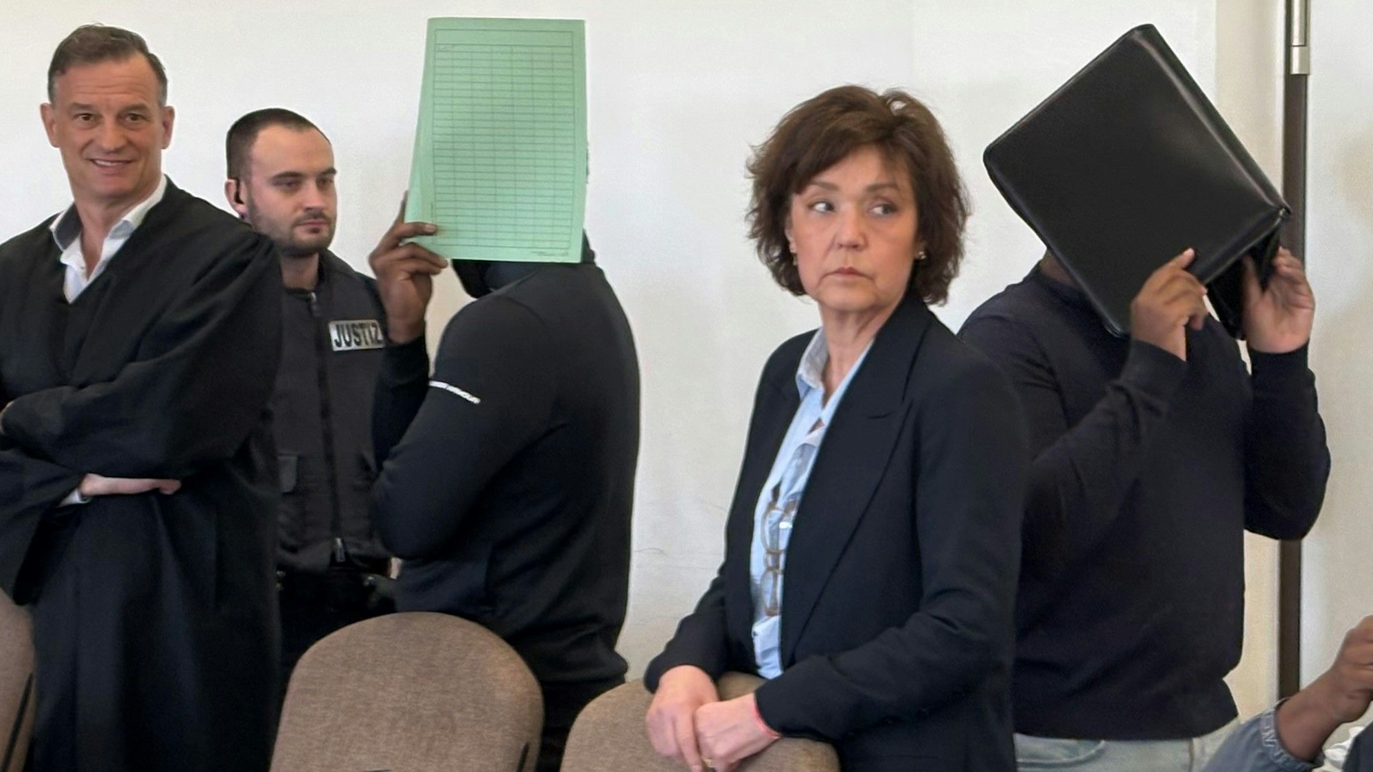 Zwei Angeklagte mit Verteidiger, Dolmetscherin und Wachtmeister beim Prozess im Kölner Landgericht