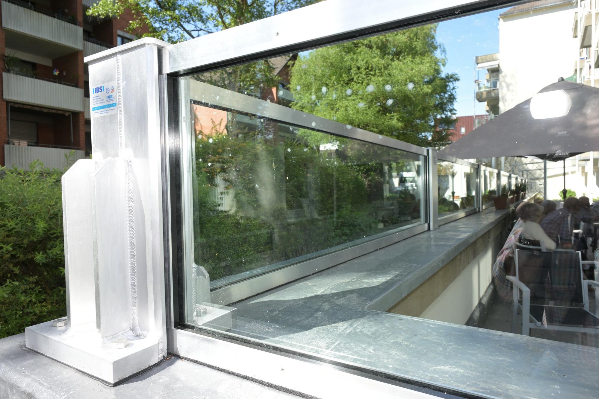 Eine Glasbarriere schützt einen Platz im Freien und Terrassentüren.