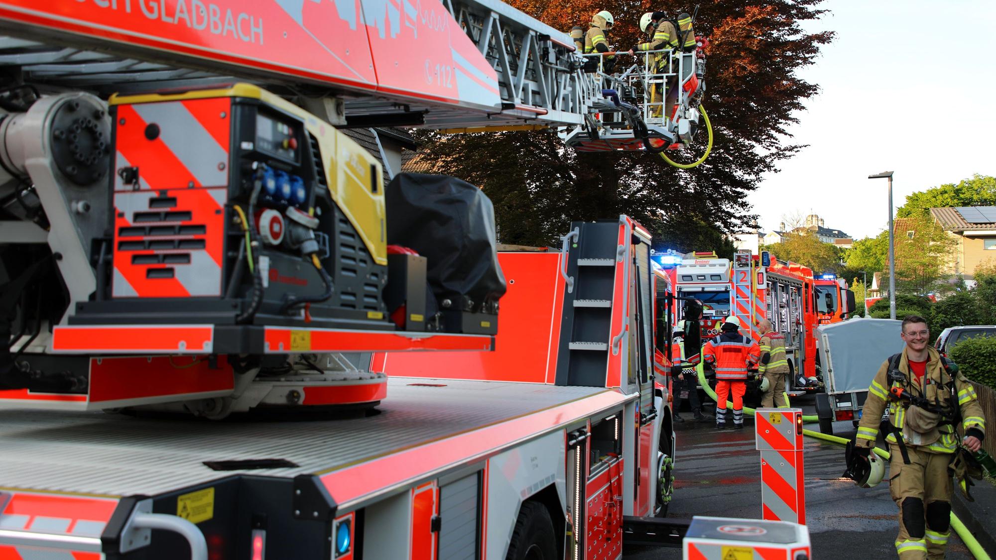 Feuerwehrfahrzeuge stehen in einer Straße, Feuerwehrleute gehen dazwischen hindurch. Am Horizont ist Schloss Bensberg zu sehen.