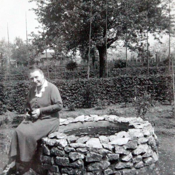 Chistine Jung sitzt in ihrem Garten auf dem Rand eines Brunnens und lächelt in die Kamera. Das Bild ist 1934 aufgenommen worden.