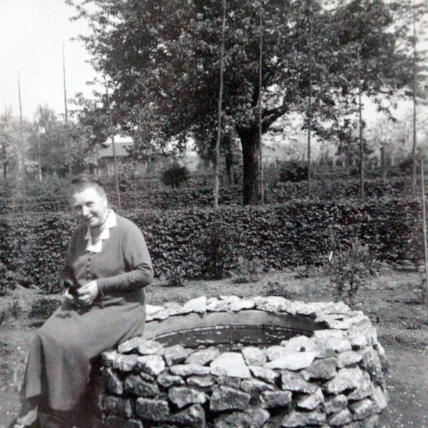 Chistine Jung sitzt in ihrem Garten auf dem Rand eines Brunnens und lächelt in die Kamera. Das Bild ist 1934 aufgenommen worden.