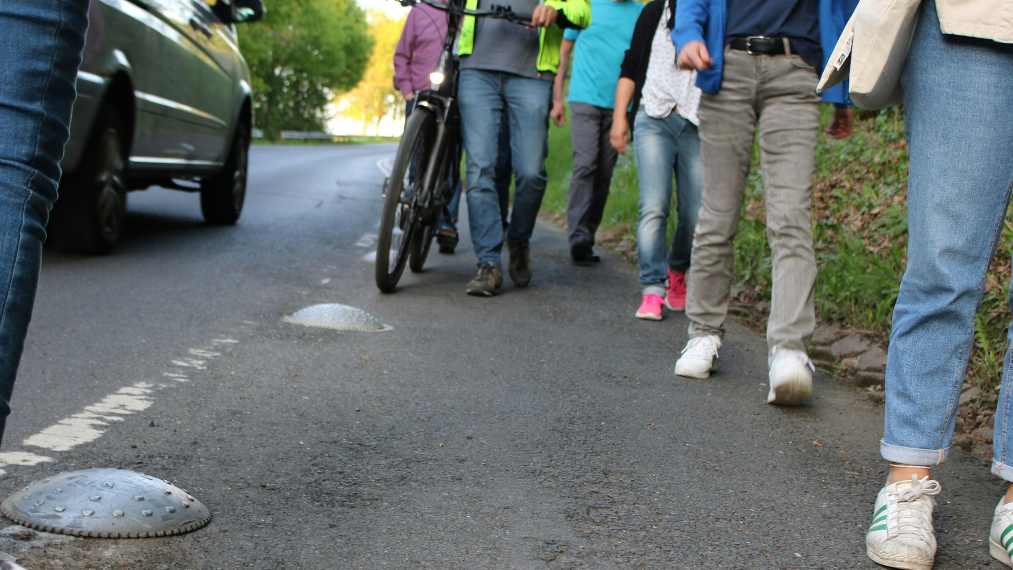 Ein durch niedrige Metallteller abgegrenzter Fußweg führt entlang der Landstraße zum Honrather Bahnhof. Viele Anwohner fühlen sich hier nicht sicher.