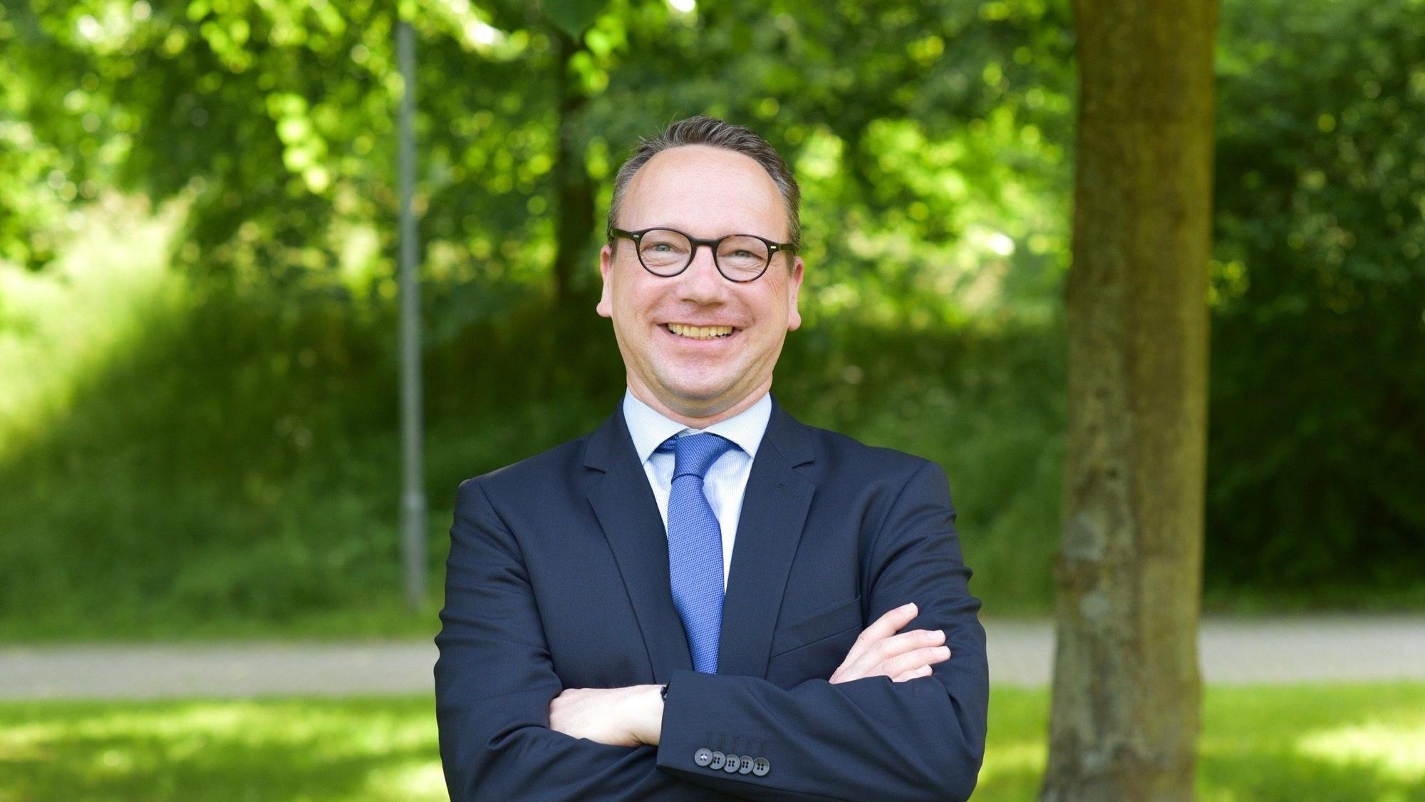 Benjamin Limbach steht im Grünen und lacht in die Kamera.