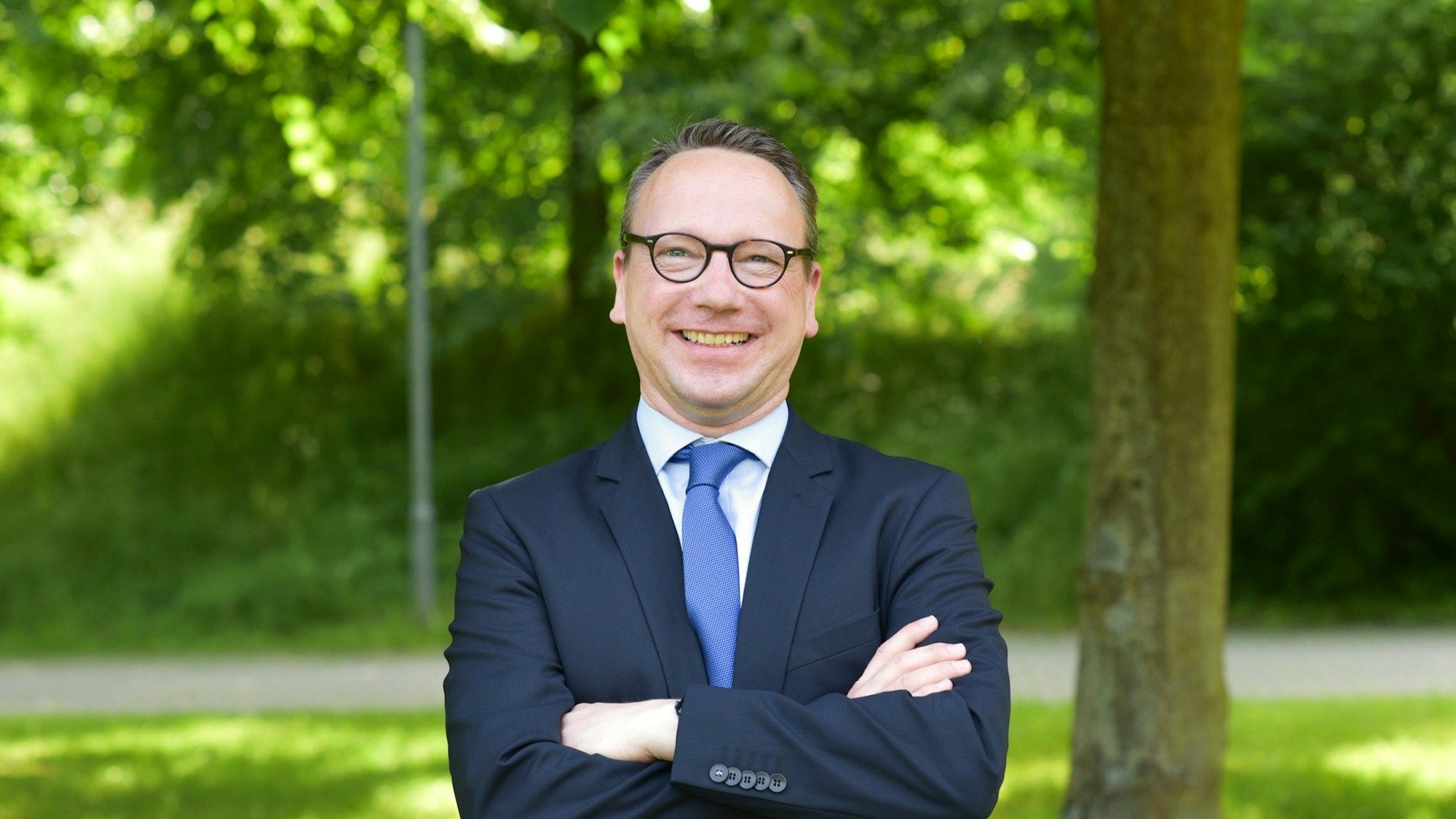 Benjamin Limbach steht im Grünen und lacht in die Kamera.