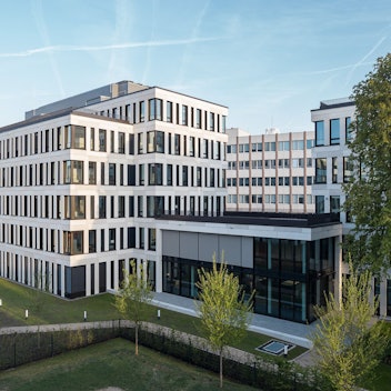 Ein neues mehrgeschossiges Bürogebäude steht an einer Straße.