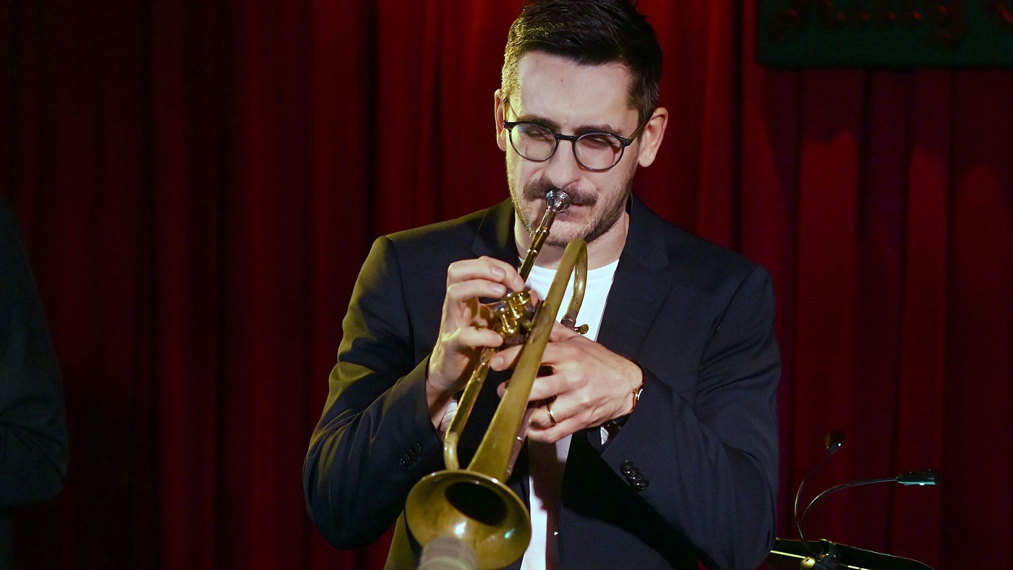 Maik Krahl trägt ein dunkles Jackett zum weißen Shirt und bläst in seine Trompete