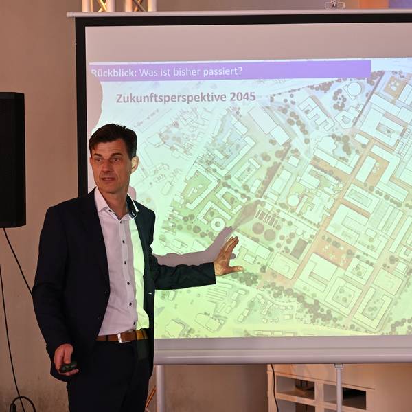 Oliver Brügge steht vor einer Leinwand ., wo ein Plan vom Zanders-Gelände abgebildet ist.