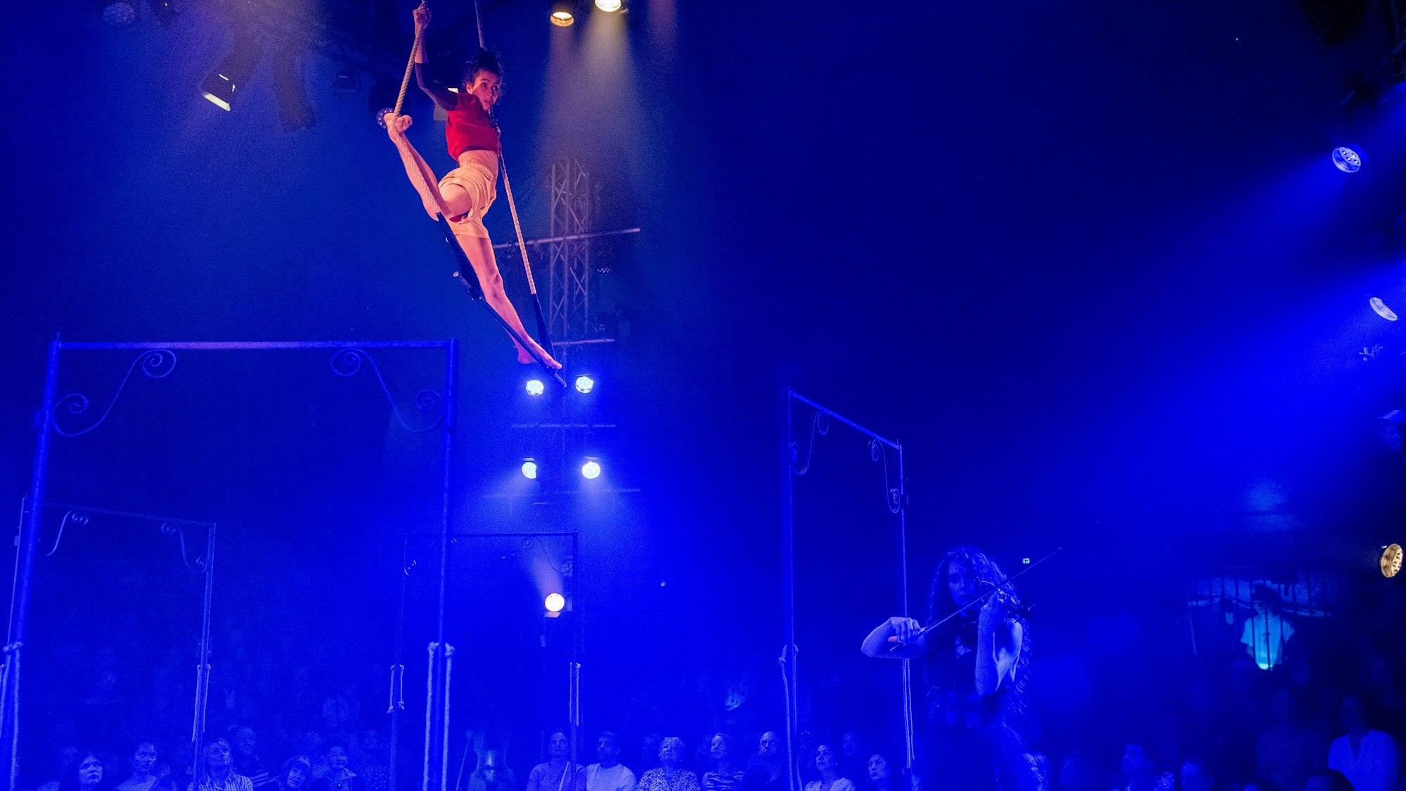 Eine Akrobatin in der Luft in Seilen und eine Geigerin bei der Zirkusshow „CARROUSSEL“ des Cirque Bouffon im Frühjahr 2025.