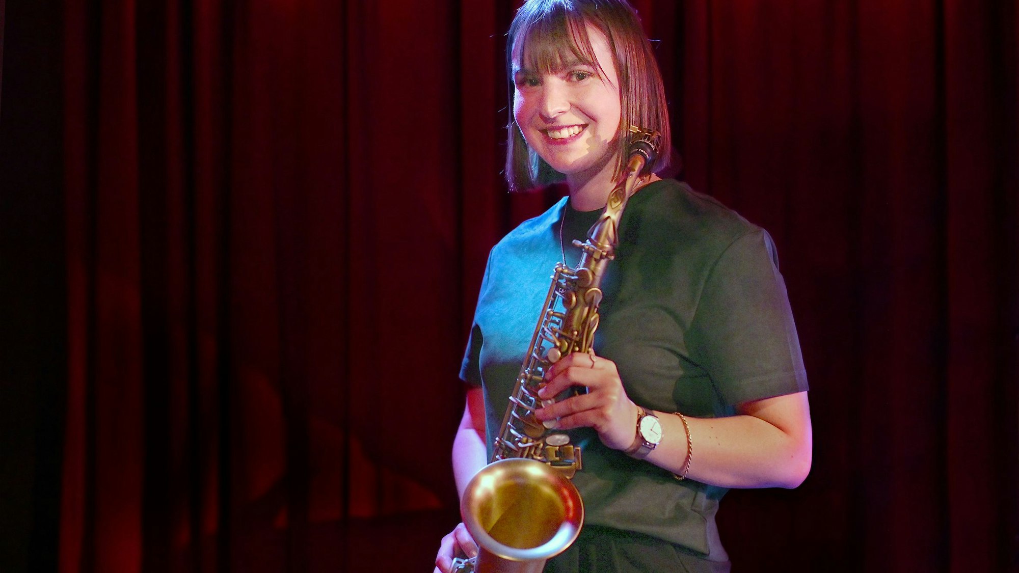 Paul Steimer trägt ein grünes Oberteil und hält ihr Saxofon.