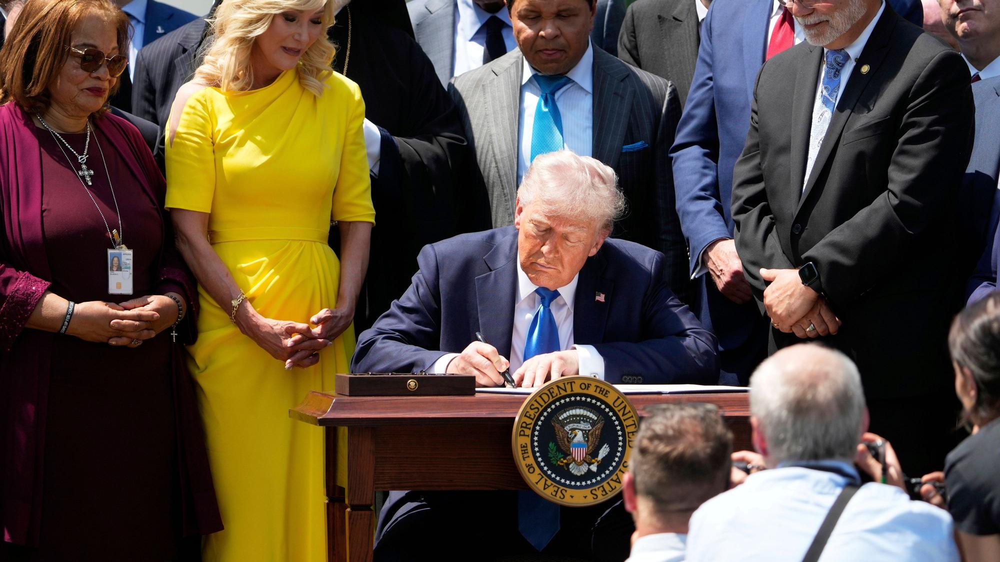 US-Präsident Donald Trump unterzeichnet, umgeben von religiösen Würdenträgern, eine Durchführungsverordnung auf einer Veranstaltung am National Day of Prayer im Rosengarten des Weißen Hauses.