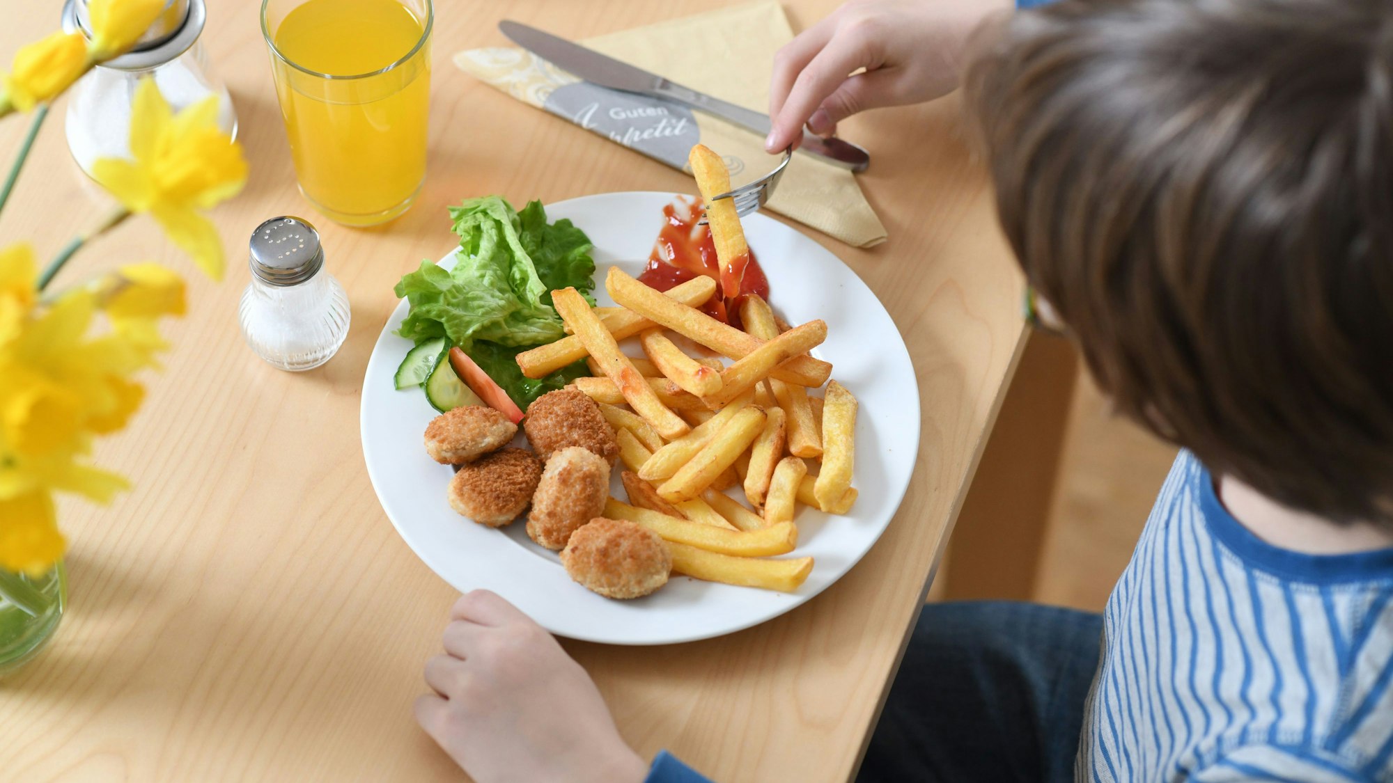 Ein Kind isst Pommes mit Fleisch: Der designierte Agrarminister Alois Rainer hat eine Debatte über Fleisch auf den Speiseplänen von Kitas und Schulen ausgelöst. (Archivbild)