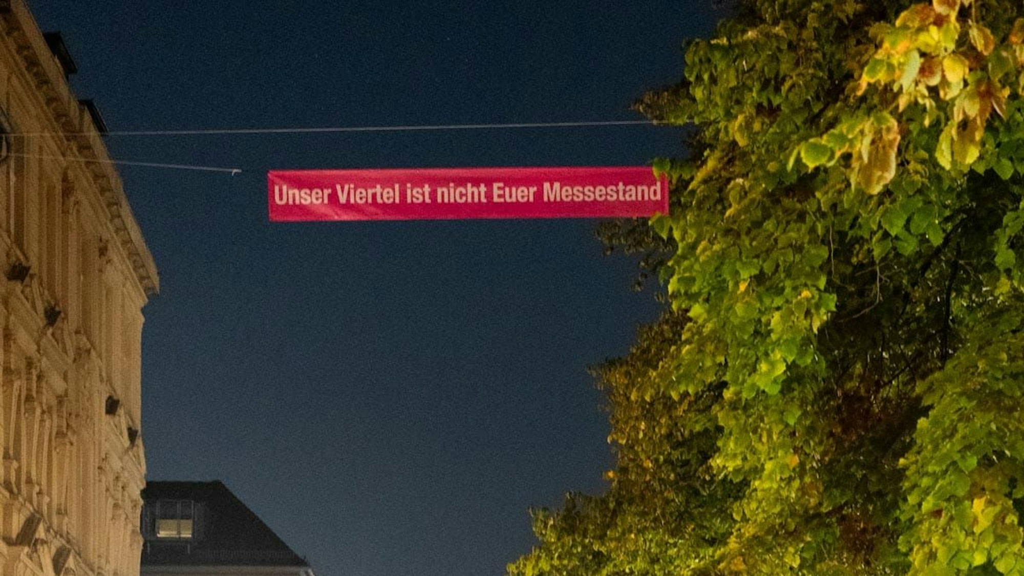 Das Bild zeigt ein Banner mit der Aufschrift „Unser Viertel ist nicht Euer Messestand“.