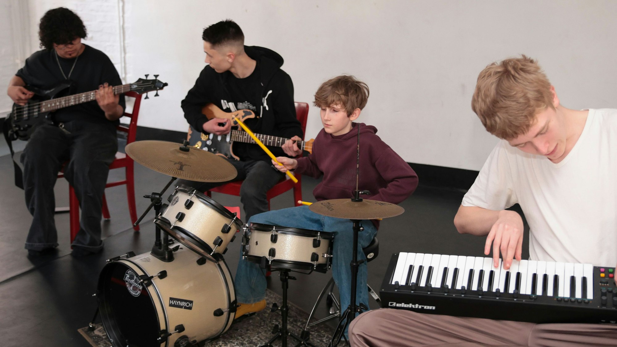 Vier junge Musiker sitzen an ihren Instrumenten