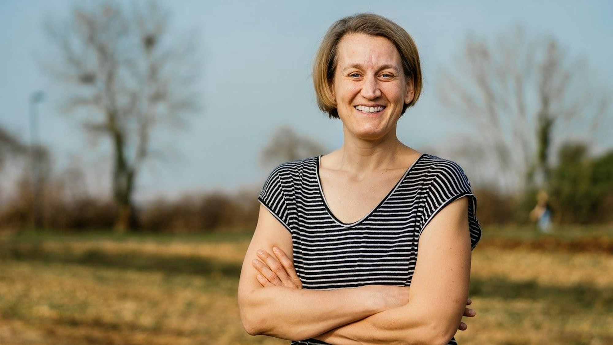 Friederike Hoffmann steht im T-Shirt draußen auf einem Feld.