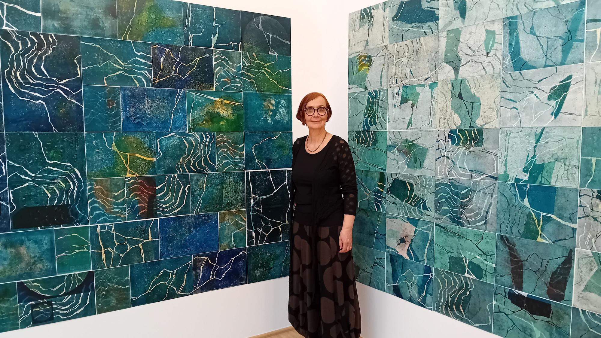 Die Künstlerin vor einer Reihe von blauen Bildern.