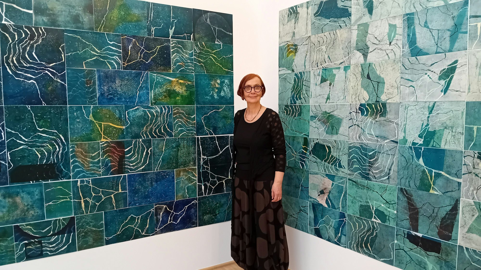 Die Künstlerin vor einer Reihe von blauen Bildern.