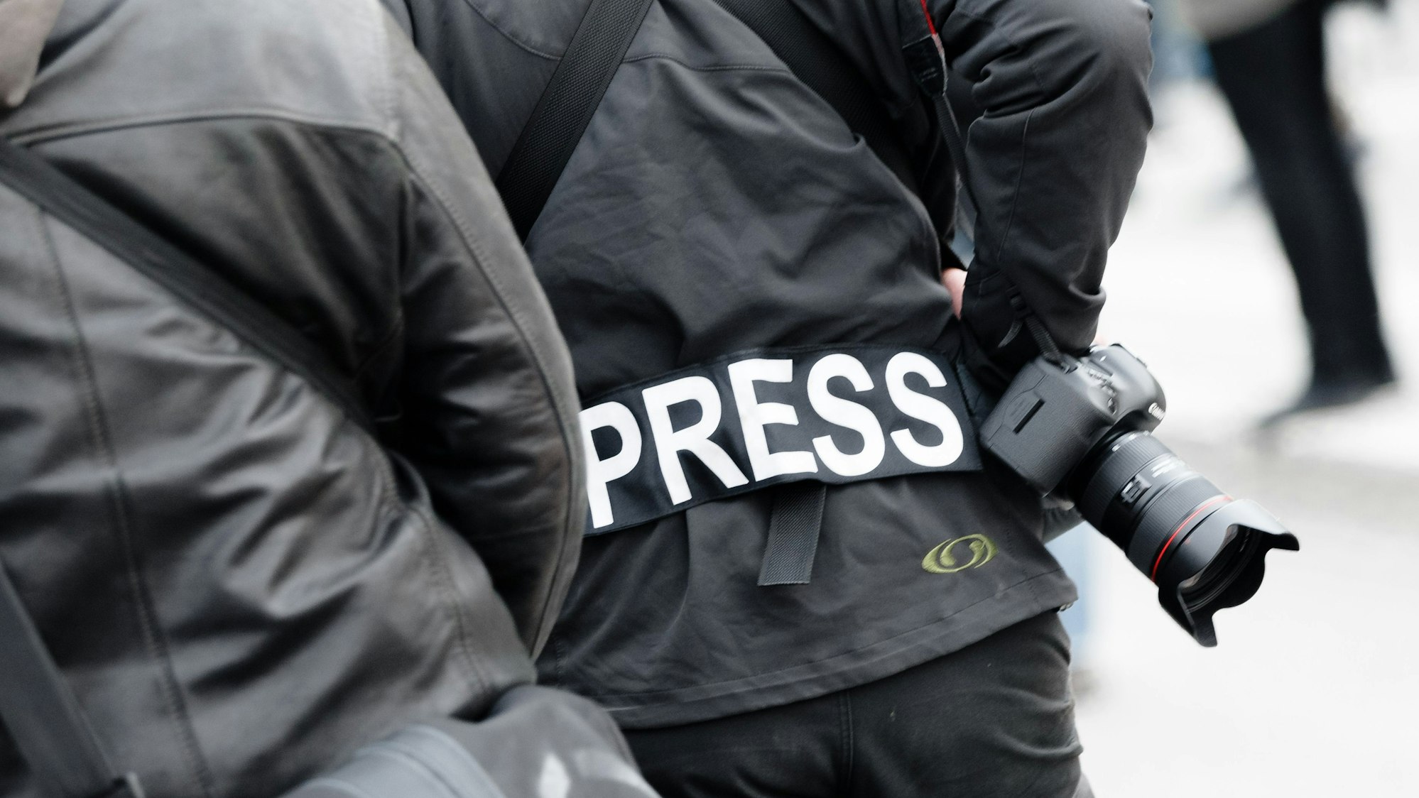 Ein Fotoreporter trägt auf einer Demonstration einen Aufnäher mit dem Text ´PRESS» auf seiner Jacke, um sich gegenüber Polizei und Demonstranten als Journalist zu kennzeichnen.