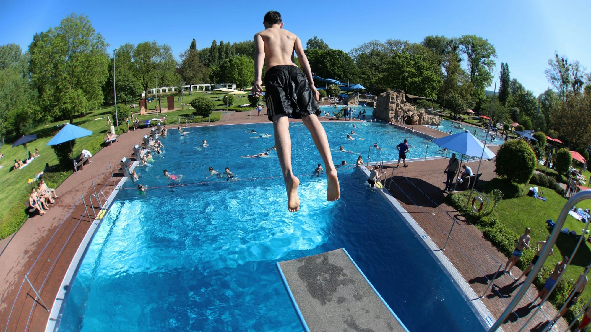 Ein Jugendlicher springt von einem Drei-Meter-Brett ins Freibad auf der Insel Grafenwerth