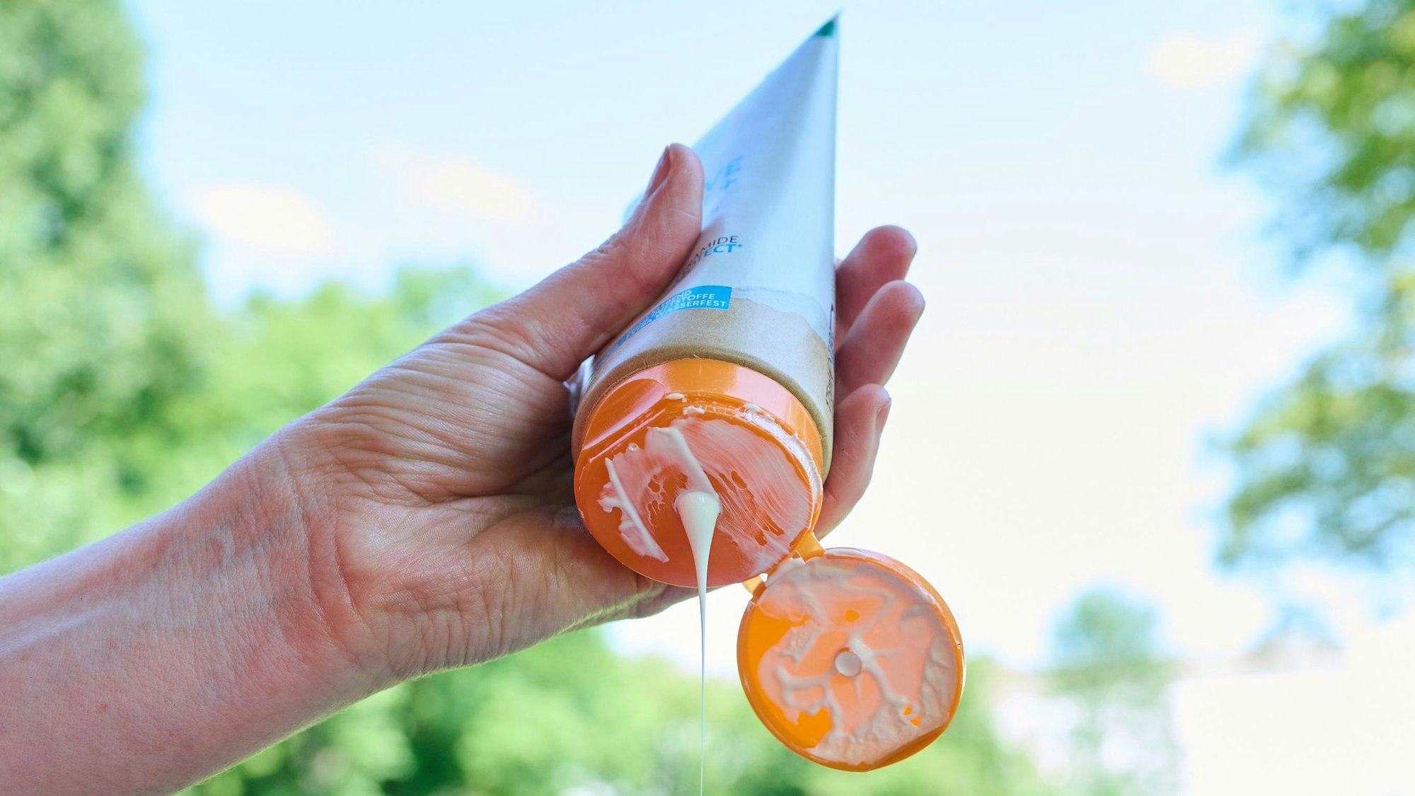 Eine Frau nimmt sich Sonnenmilch aus der Tube.