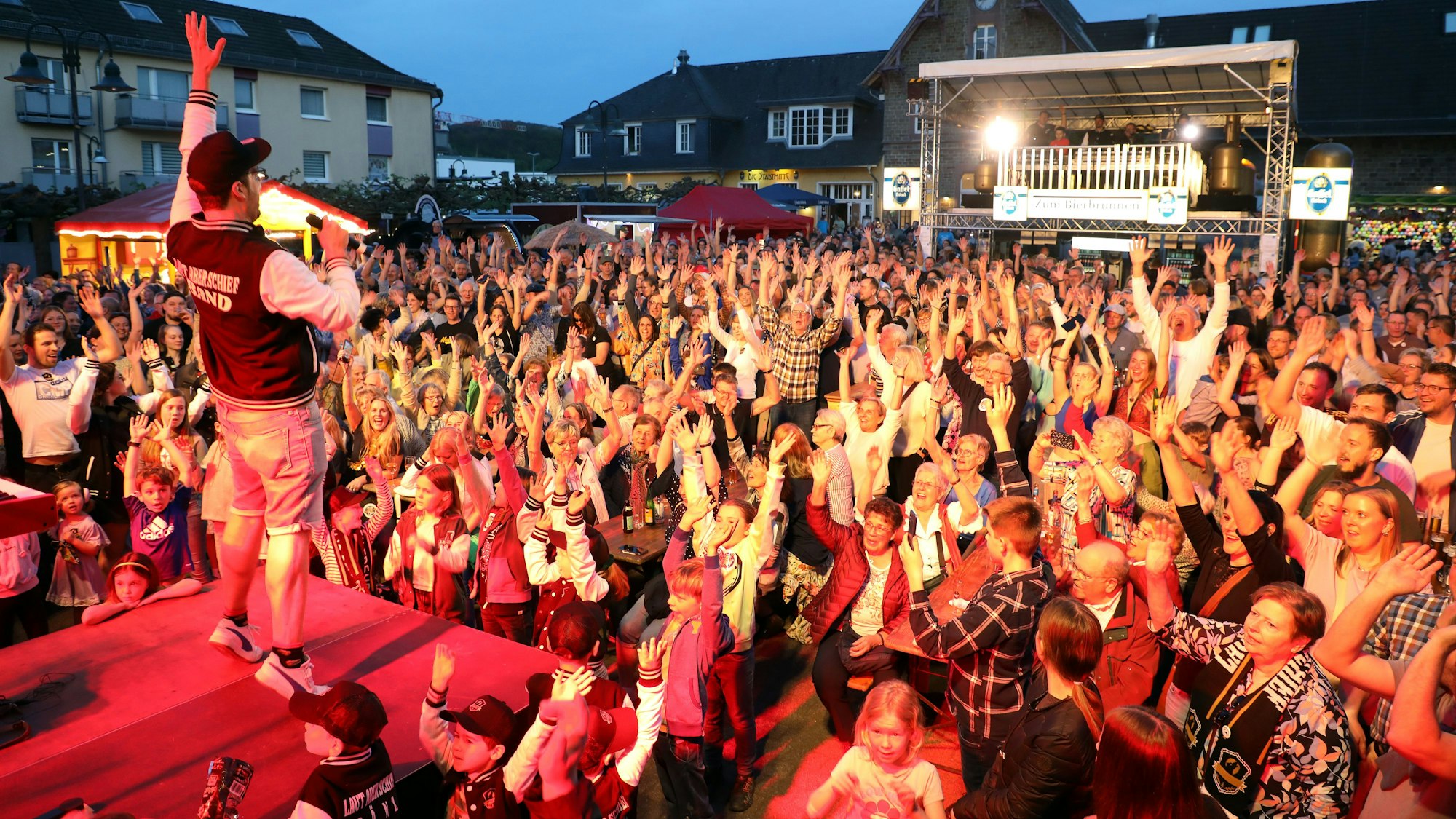 Vor einer tanzenden Menschenmenge tritt ein Sänger unter freiem Himmel auf.
