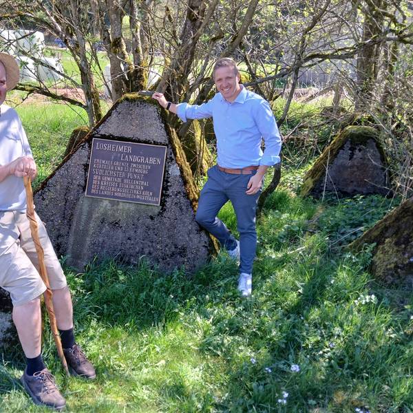Ralf Spilles und Landrat Markus Ramers sind an der Erinnerungstafel an den Losheimer Landgraben zu sehen.