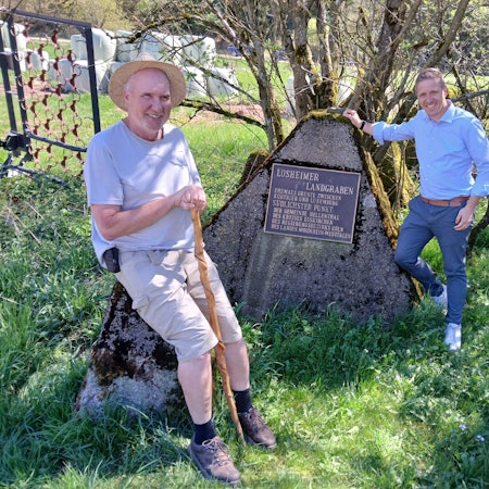 Ralf Spilles und Landrat Markus Ramers sind an der Erinnerungstafel an den Losheimer Landgraben zu sehen.