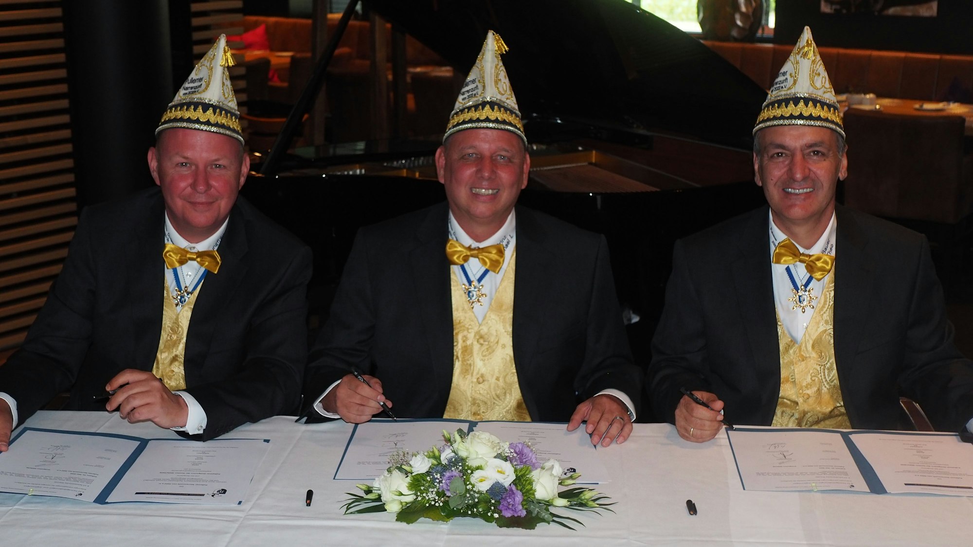 Drei Männer, sie alle tragen Karnevalskappen (Schiffchen).