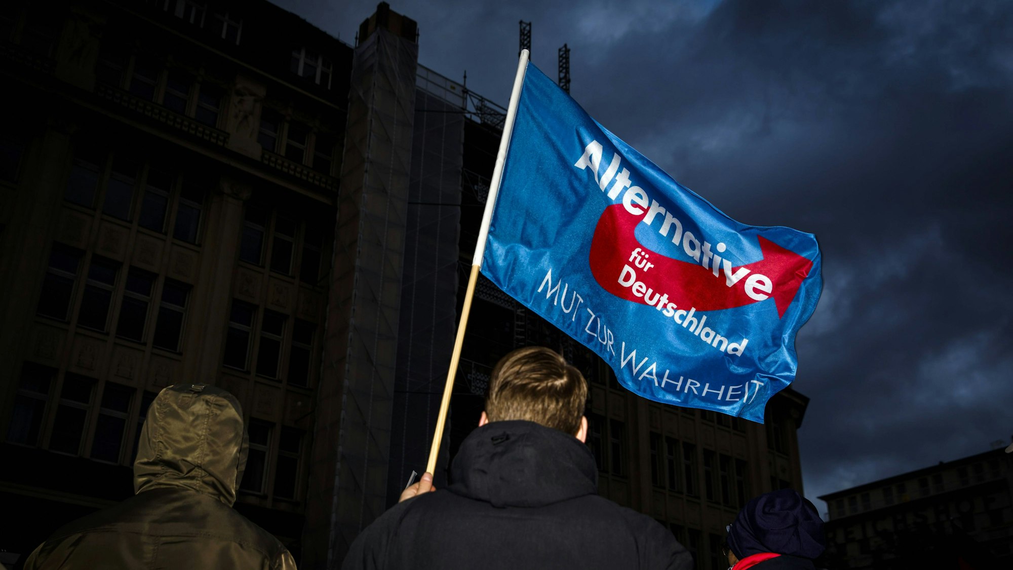 Ein Teilnehmer einer Demonstration der Partei AfD schwenkt eine Fahne