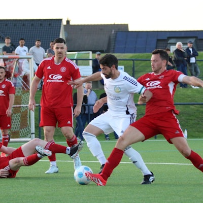 Zülpichs Kapitän Georg Salmon attackiert einen Gegner. Lucas Carell und Alexander Ems schauen stehend, Felix Faure sitzend zu.
