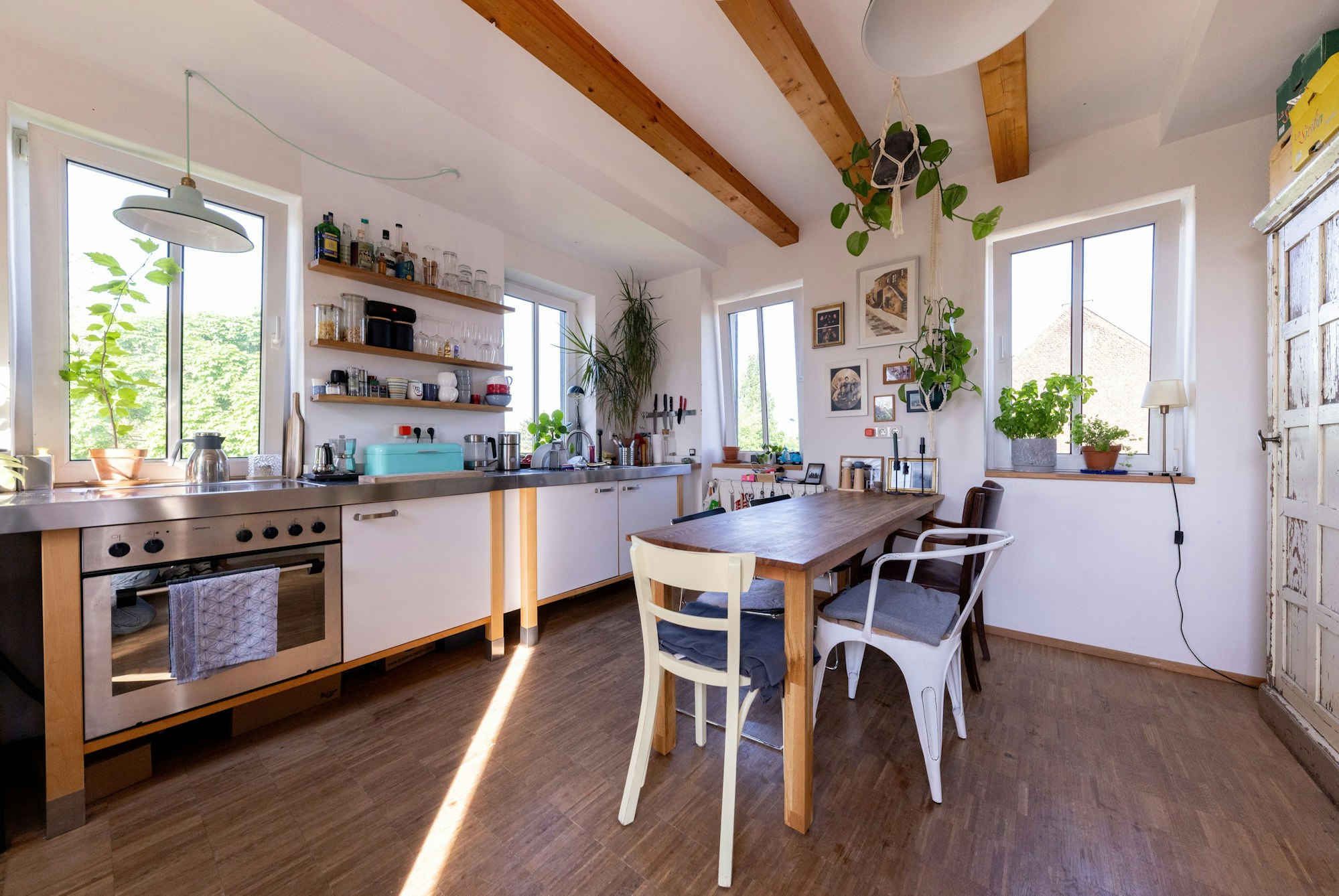 In einer Küche mit vielen Fenstern sind Holzbalken in der Decke zu erkennen.