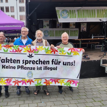 Vier Männer halten ein Plakat.