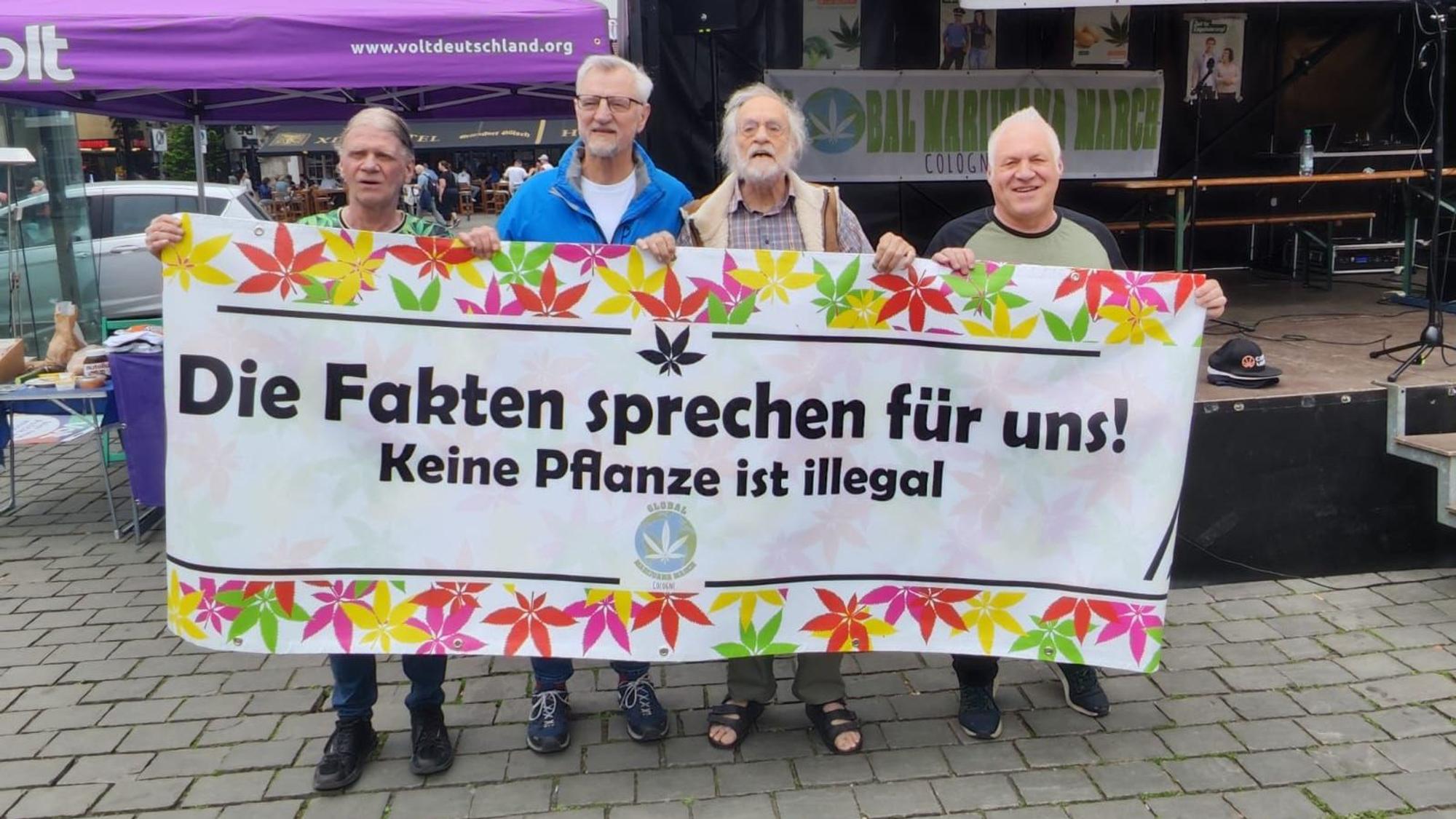 Vier Männer halten ein Plakat.