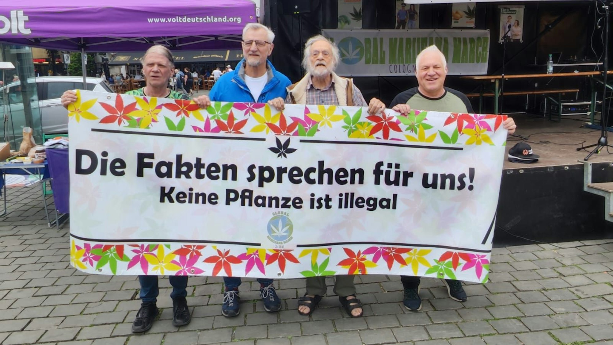 Vier Männer halten ein Plakat.