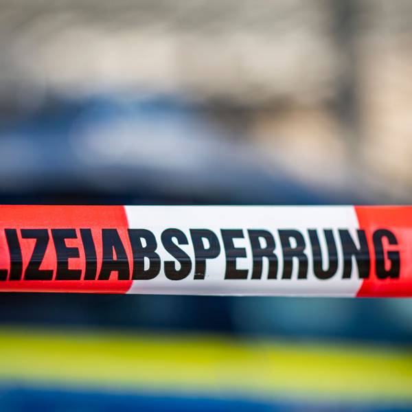 Ein Absperrband mit der Aufschrift „Polizeiabsperrung“ ist vor einem Polizeiwagen aufgespannt.