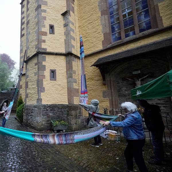 Einige Menschen stehen vor der Kirche und breiten den langen Wollschal aus.