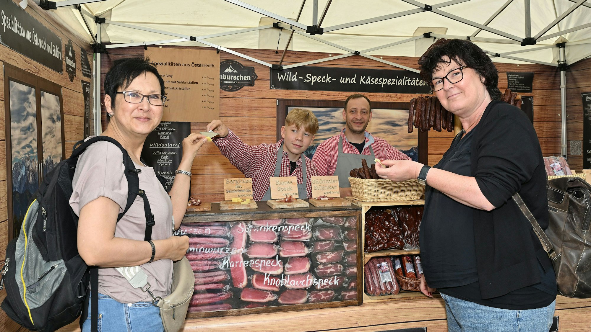 Zwei Besucherinnen probieren an einem Stand Wild und Käse.
