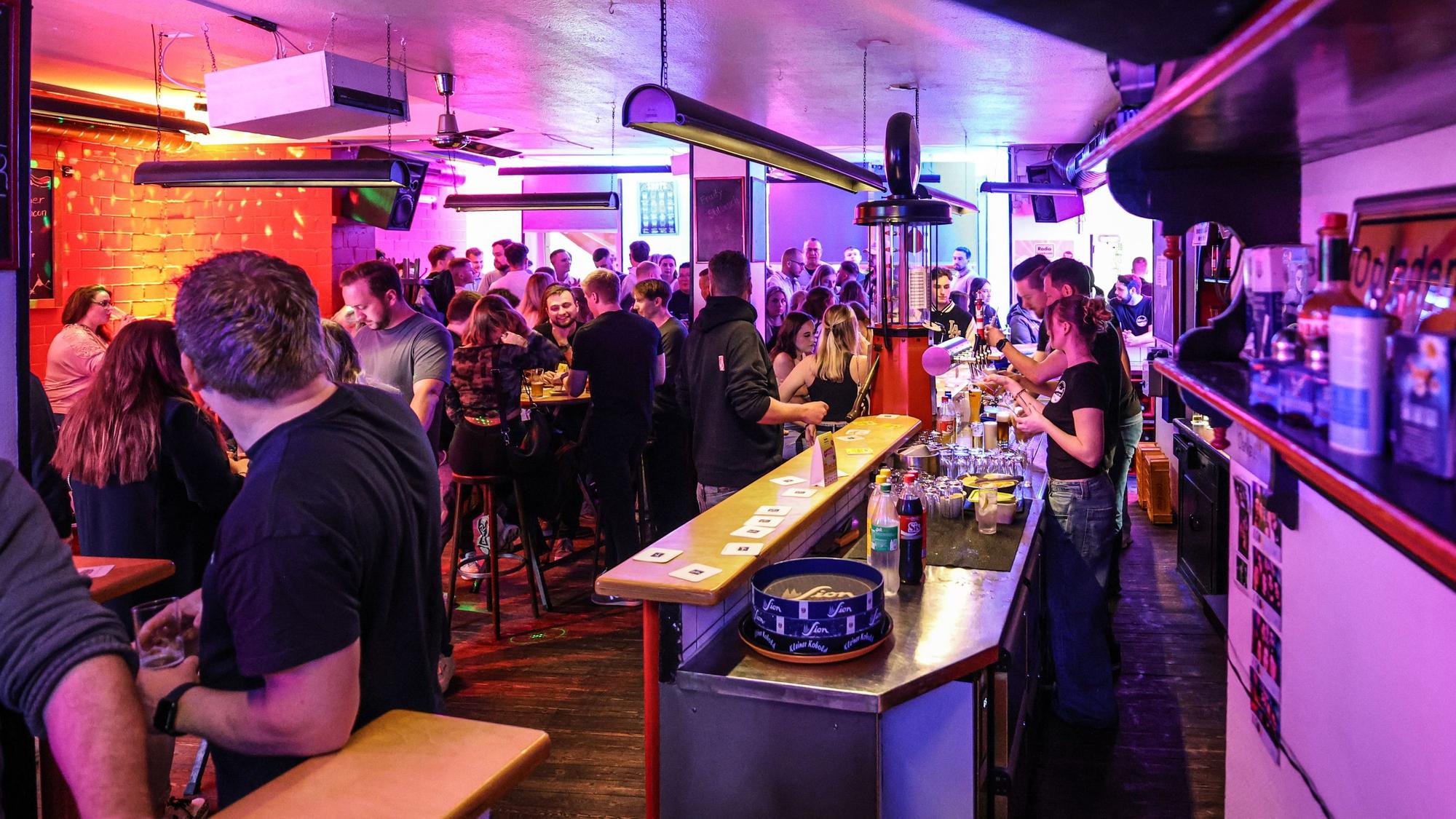Menschen tanzen und trinken in einer Kneipe.