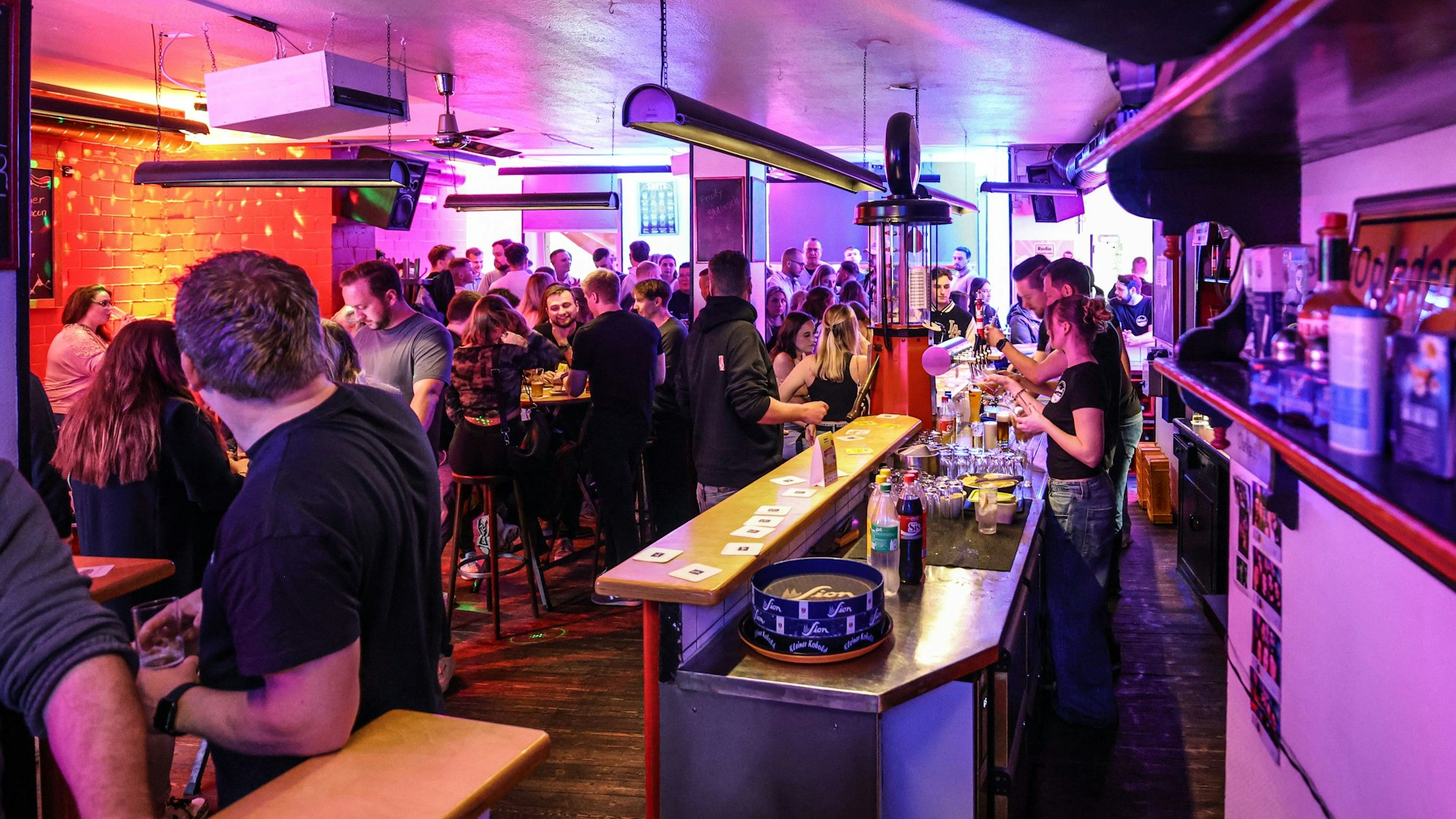 Menschen tanzen und trinken in einer Kneipe.