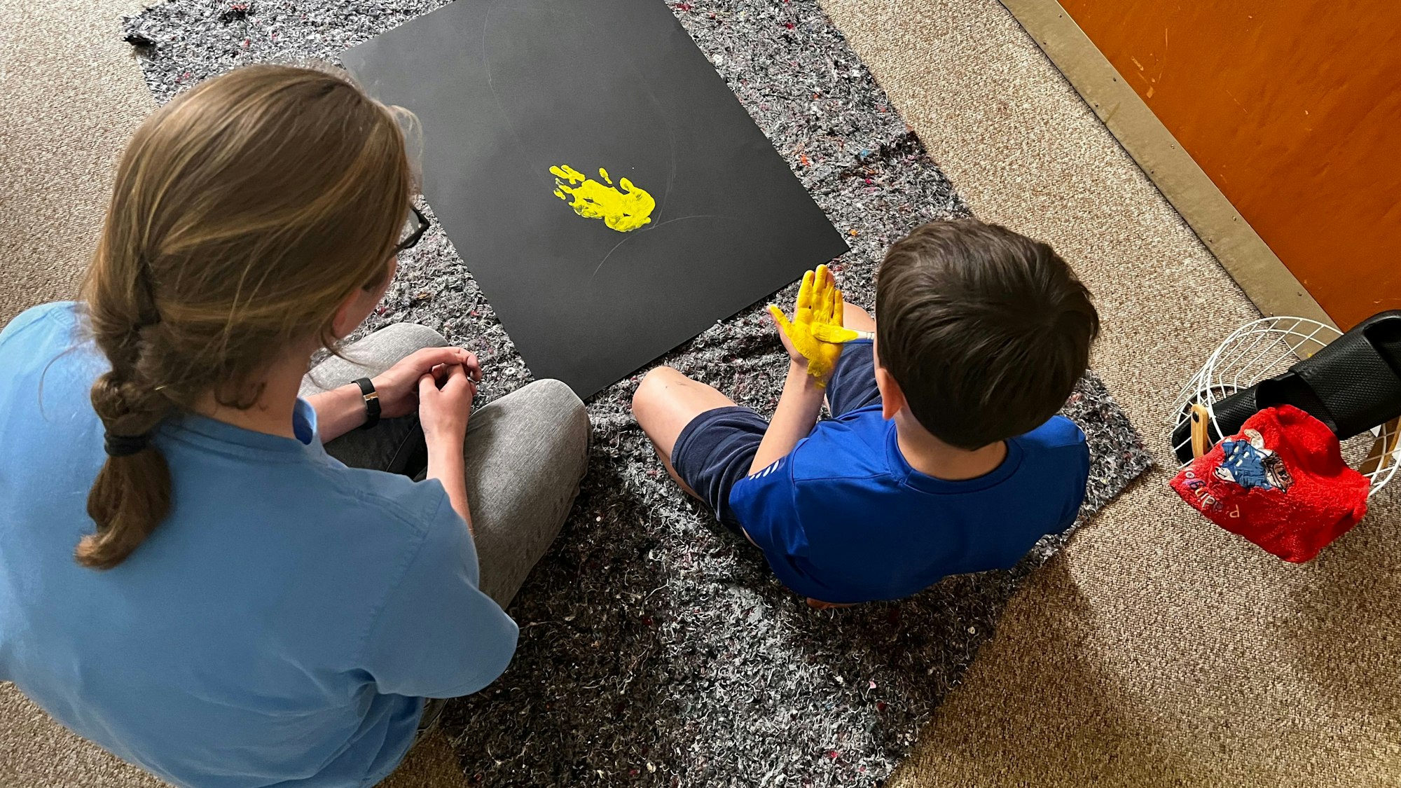 Ein Kind malt auf einem Bogen Papier mit den Händen.