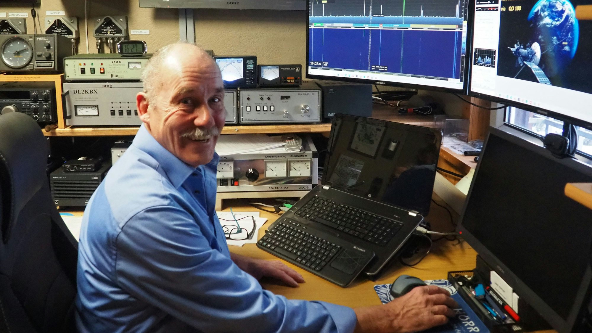 Funker Klaus Baer inmitten seines Equipments, das um ihn herum steht.