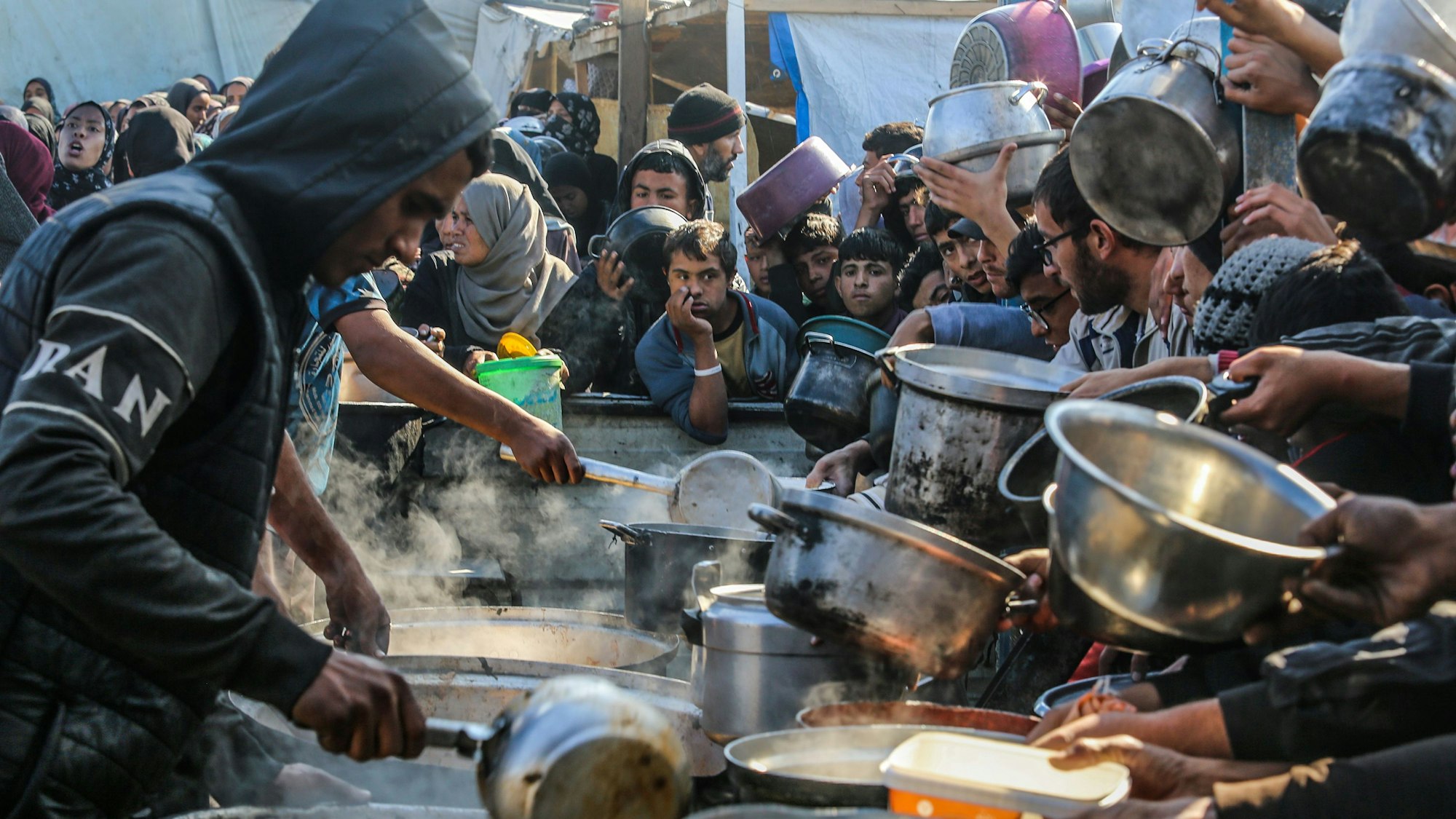 ARCHIV - 02.01.2025, Palästinensische Gebiete, Rafah: Menschen versammeln sich, um Mahlzeiten von der Wohltätigkeitsküche (Tekka) in Rafah zu erhalten, da die Palästinenser angesichts des Mangels an Mehl und Hilfsgütern und der anhaltenden Schließung der Grenzübergänge im Rahmen der Belagerung des Gazastreifens von einer Hungersnot bedroht sind. (zu dpa: «UN weisen israelischen Hilfsgüterplan zurück») Foto: Abed Rahim Khatib/dpa +++ dpa-Bildfunk +++
