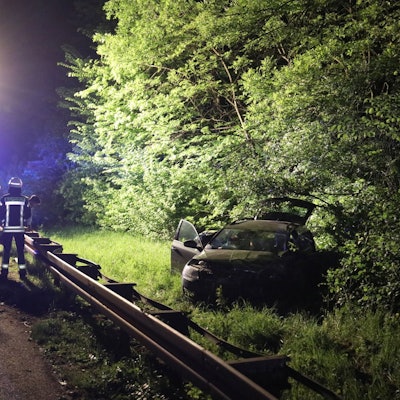 Der Scheinwerfer auf einem Feuerwehrwagen leuchtet die Unfallstelle aus, der beschädigte Pkw steht im Grünstreifen hinter der Leitplanke.