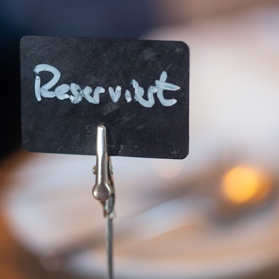 Eine Tafel mit der Aufschrift „Reserviert“ steht auf einem gedeckten Tisch.