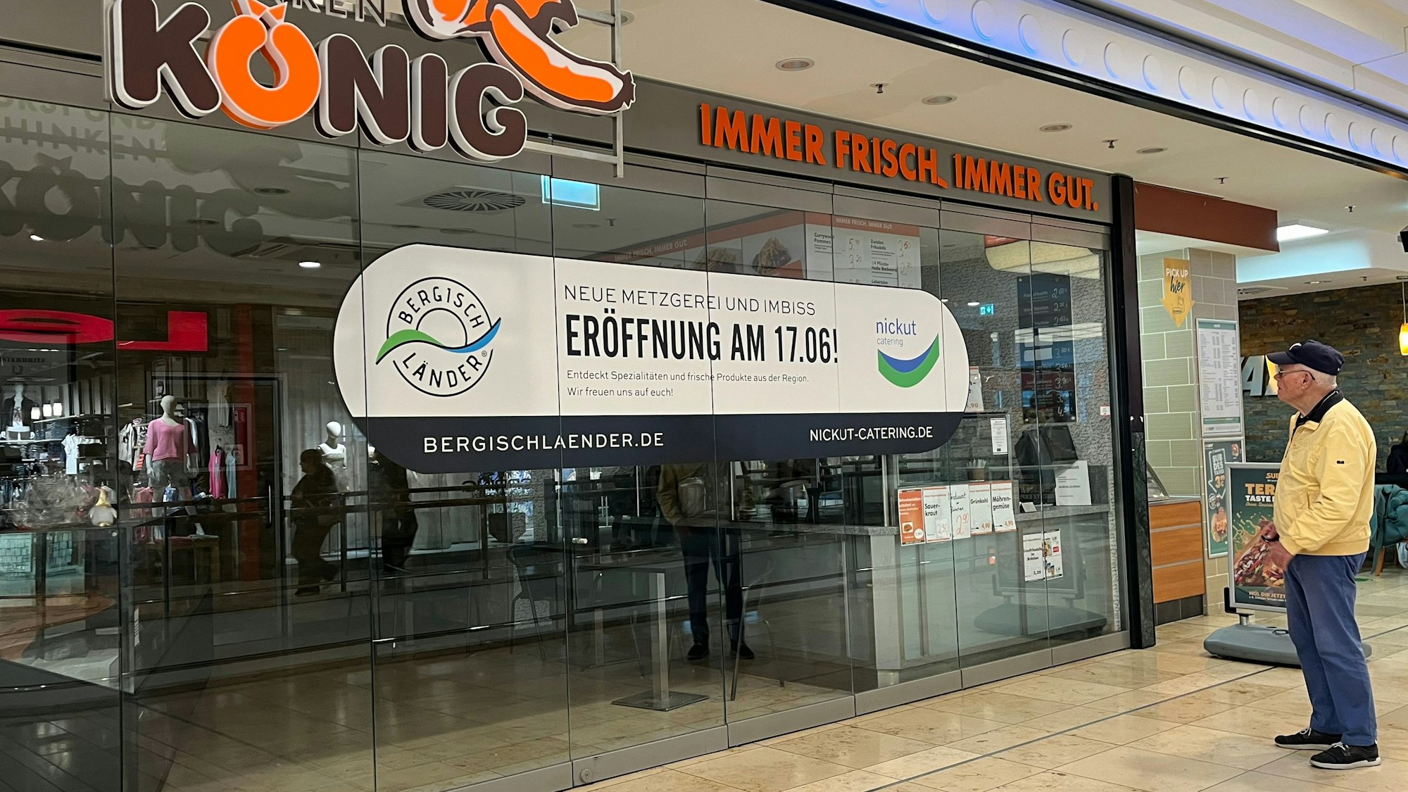 Ein Mann steht vor einer Schaufenster-Scheibe mit einer Geschäftsankündigung.